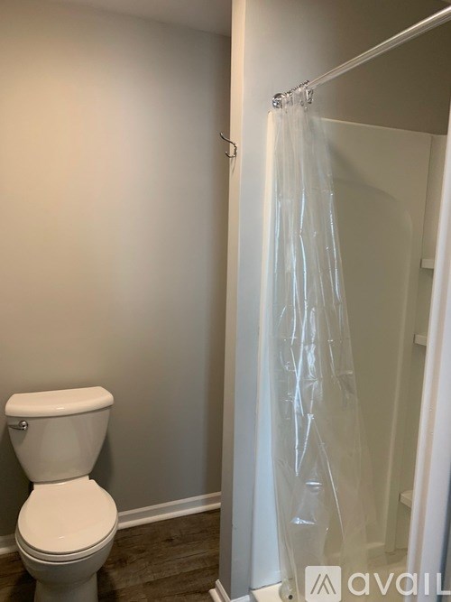 A white toilet in a bathroom with a shower curtain hanging on the door.