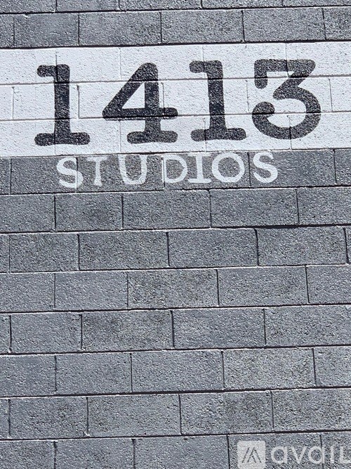 A grey brick wall with the number 1413 and the word studios written on it.