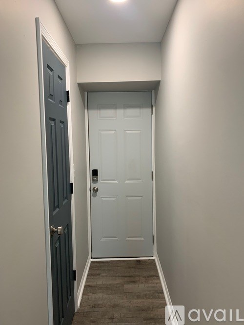 A hallway with a white door and a black door on the left.