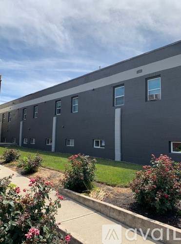 A grey building with a white pipe on the side and windows on the front.