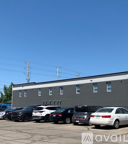 A parking lot with several cars parked in front of a grey building.
