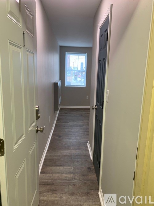 A hallway with a door on the left and a window in the distance.