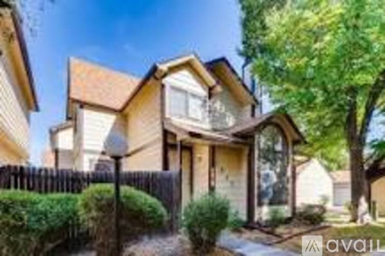 A house with a brown roof and a white fence is for sale.