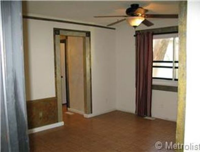 A room with a ceiling fan and a door.