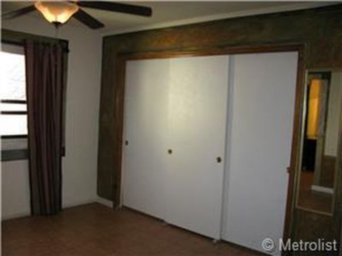 A room with a white door and a ceiling fan.
