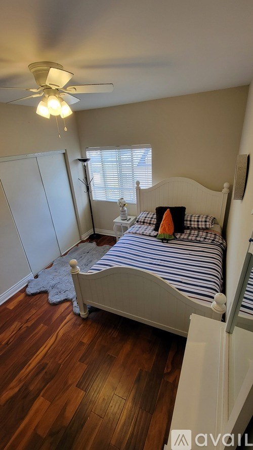 A bedroom with a bed, a ceiling fan, and a window with blinds.