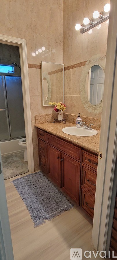 A bathroom with a sink, mirror, and a blue rug.