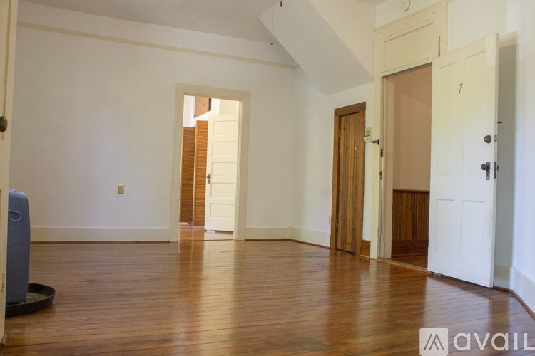 A room with wooden floors and white walls, with a door on the left and a door on the right.