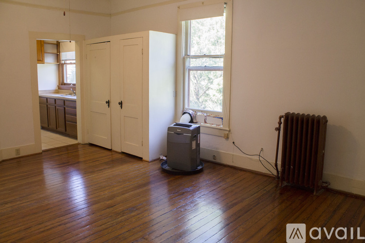 A room with wooden floors and a window with a radiator to the side.