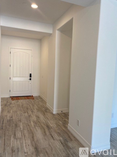 A room with a white door and wooden flooring.