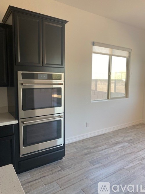 A kitchen with black cabinets and a stainless steel oven.