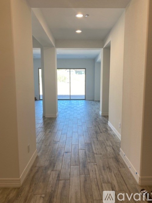 A long hallway with wood flooring and white walls.