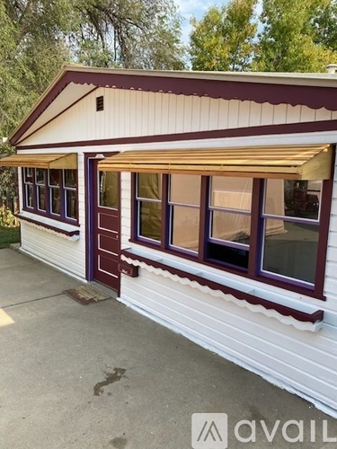 A white house with a purple trim and a brown awning.