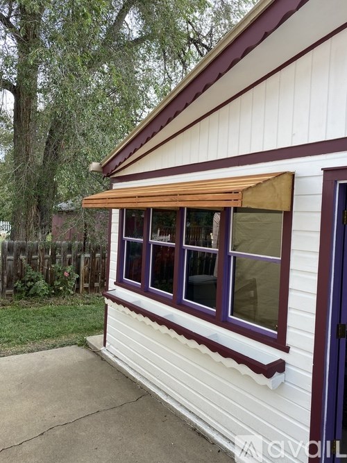 A white house with a purple trim and a brown awning.