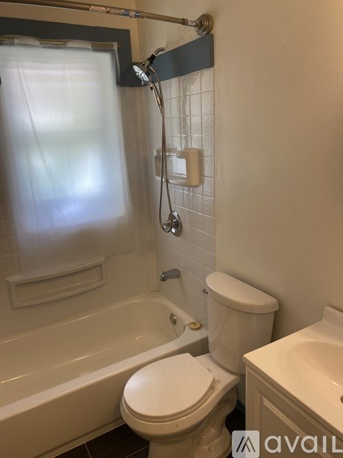 A white toilet in a bathroom with a white tub and a white sink.
