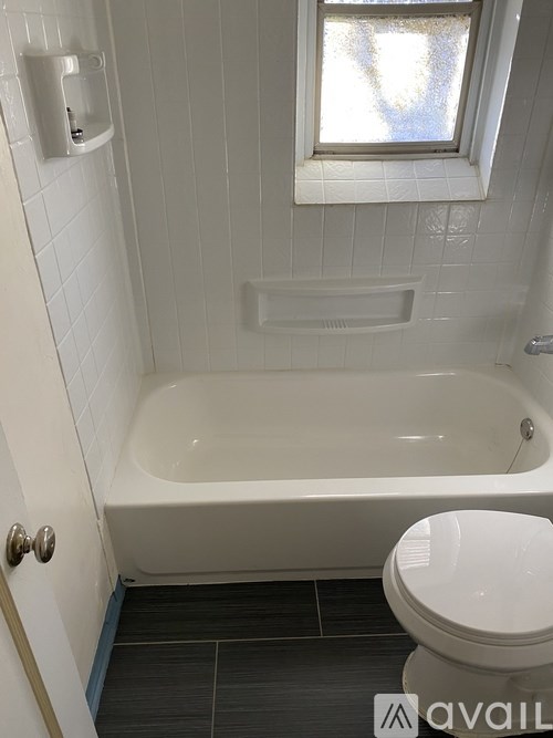 A white toilet sits next to a bathtub in a bathroom.