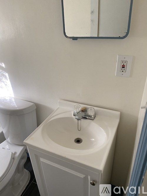A white sink in a bathroom with a toilet and mirror.