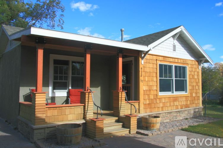A small house with a porch and a red chair.