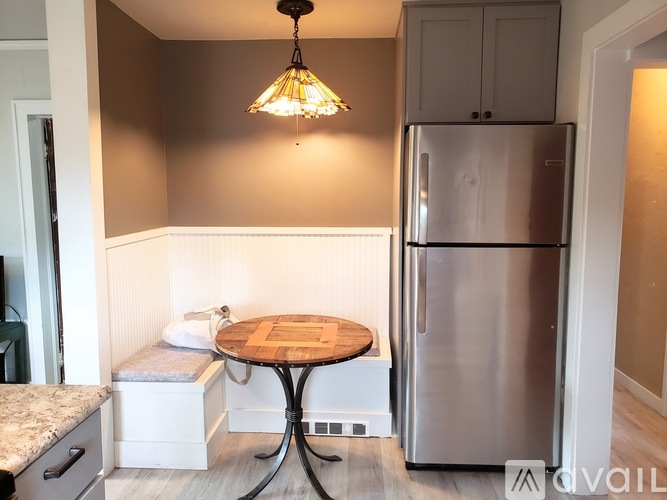 A kitchen with a stainless steel refrigerator and a round wooden table.