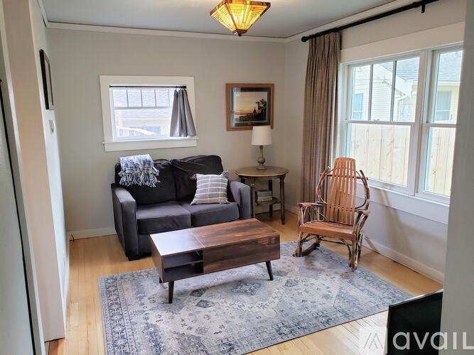 A living room with a black couch, a wooden coffee table, and a wooden chair.