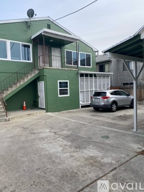 A green house with a silver car parked in front.