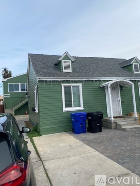 A green house with a white door and a car parked in front.