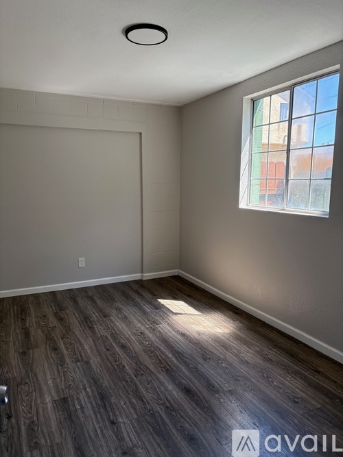 A room with wooden flooring and a window showing a view of buildings outside.