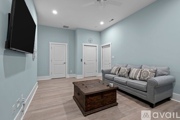 A living room with a grey couch, a wooden coffee table, and a flat screen TV mounted on the wall.