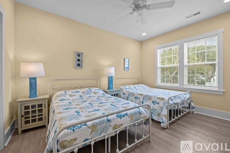 Two twin beds with blue and white bedspreads in a room with a ceiling fan.