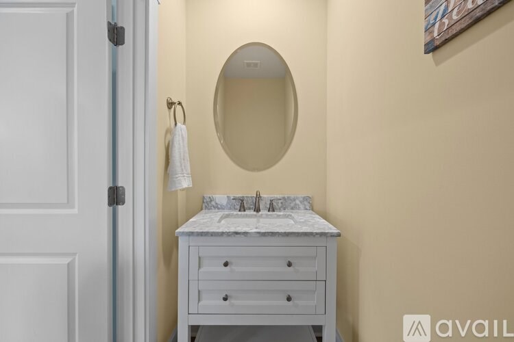 A white vanity table with a marble top and a round mirror above it.