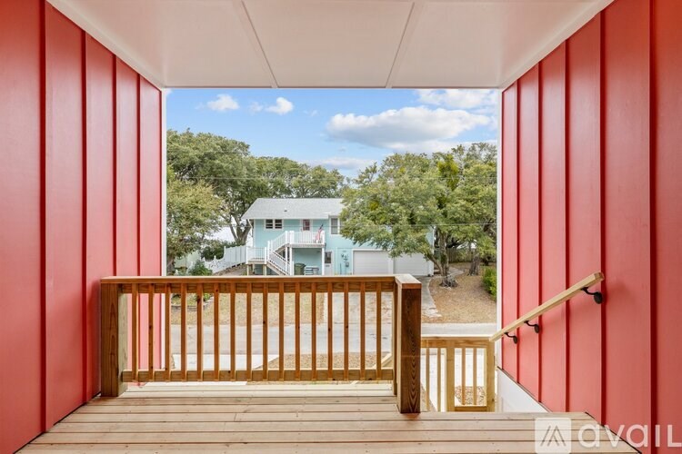 A balcony with red walls overlooks a blue house.