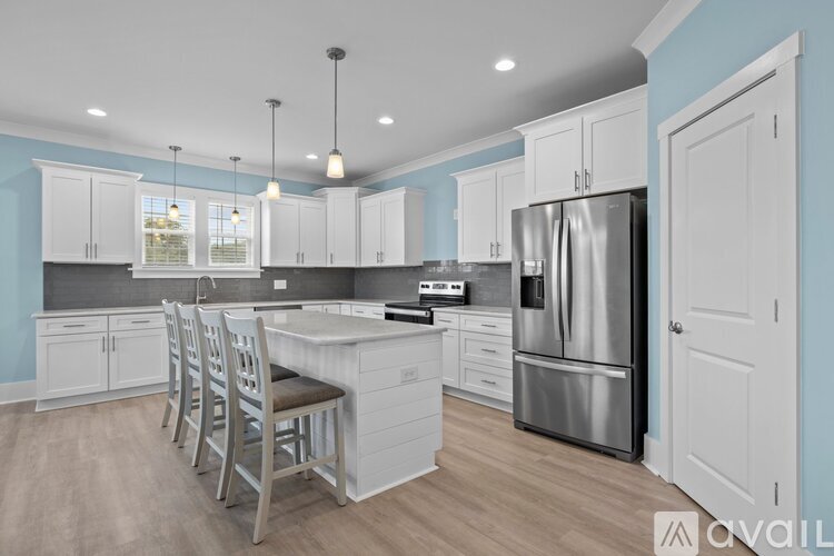 A kitchen with a large island and a stainless steel refrigerator.