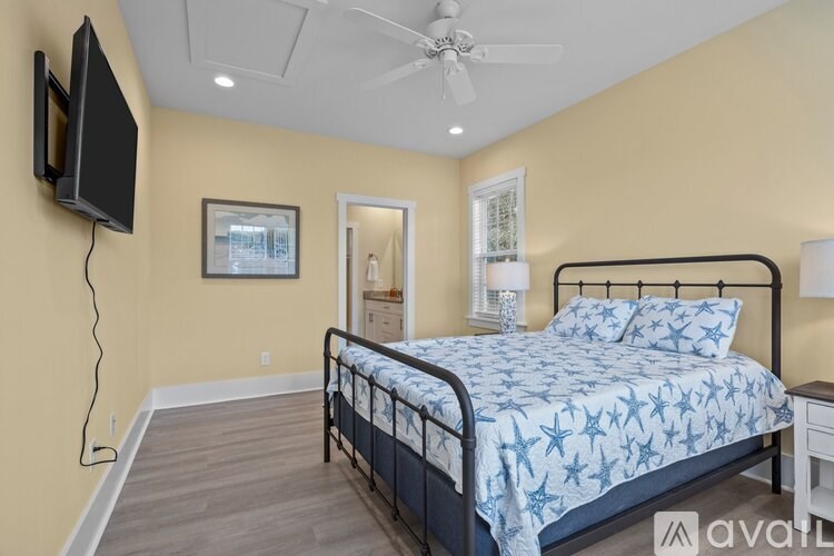 A bedroom with a bed, a ceiling fan, and a television mounted on the wall.