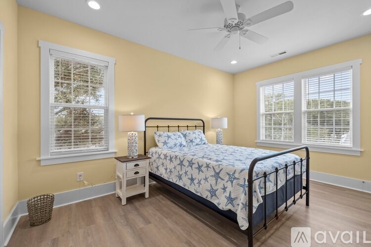 A bedroom with a bed, nightstand, and window with blinds.