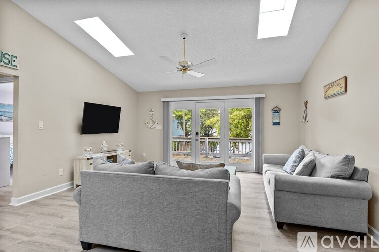 A living room with two grey couches and a flat screen TV mounted on the wall.