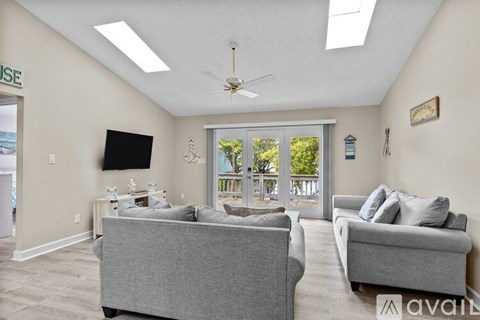 A living room with two grey couches and a flat screen TV mounted on the wall.