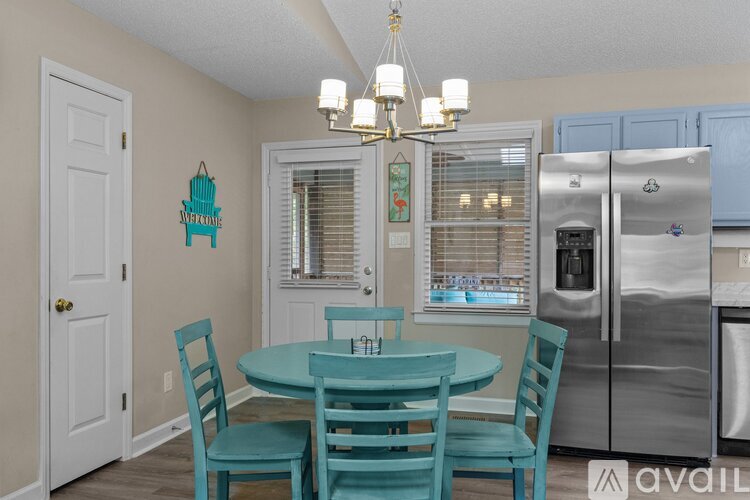 A kitchen with a table and chairs and a fridge.