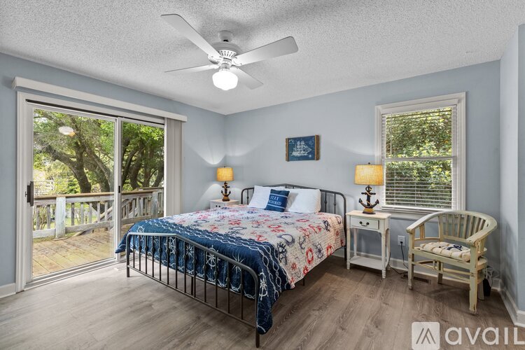 A bedroom with a bed, chair, and sliding glass doors.