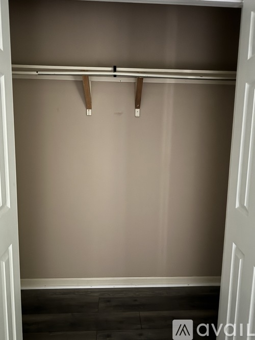 A white closet with a grey wall and wooden hangers.