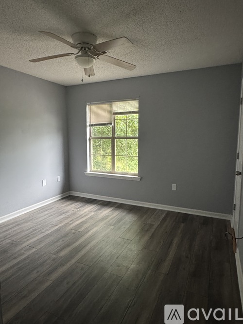 A room with a ceiling fan and a window with blinds.