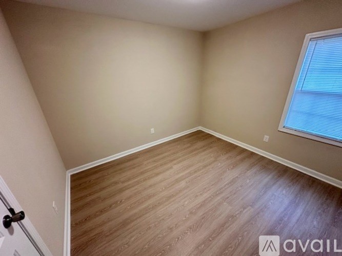 A room with wooden flooring and a window with blinds.