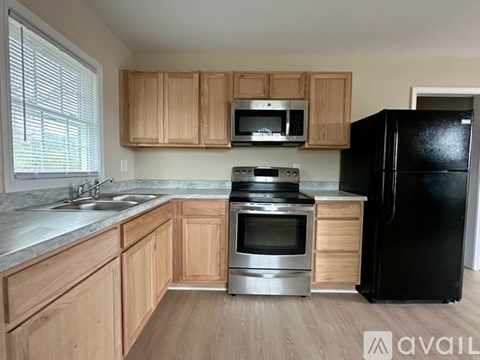 A kitchen with wooden cabinets and a black refrigerator.