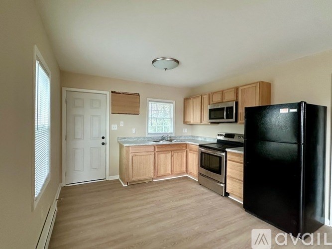 A kitchen with wooden cabinets and a black refrigerator.