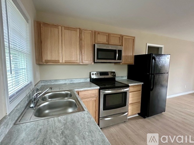 A kitchen with a black refrigerator, a stove, a microwave, and a sink.