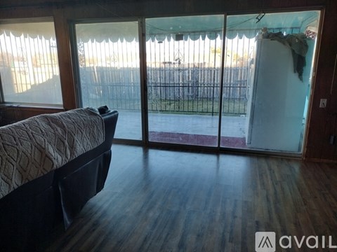 A bedroom with a bed and sliding glass doors leading to a backyard.