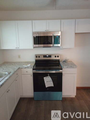 A kitchen with a stove top oven and white cabinets.