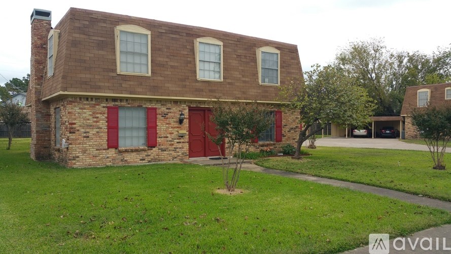 A brick house with a red door and two windows.