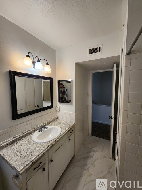 A bathroom with a sink, mirror, and a door.