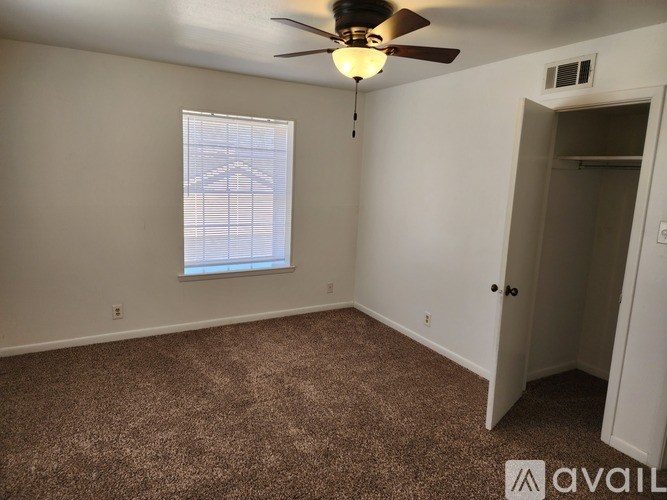 A room with a carpeted floor, a ceiling fan, and a window with blinds.
