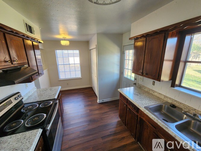 A kitchen with dark wood cabinets and a stove top oven.
